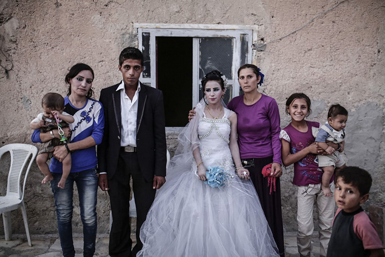 Un couple de nouveaux mariés pose avec sa famille à Kobané, le 6 décembre 2015, dans le nord de la Syrie. © Yasin Akgul / AFP